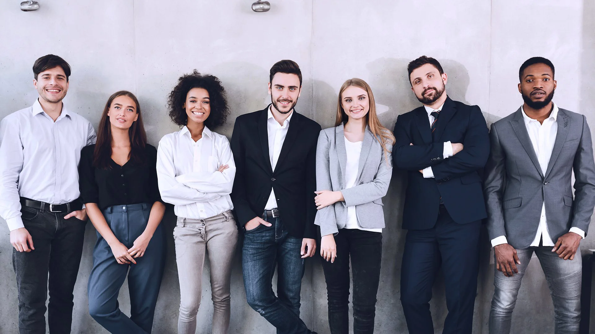 Grupo de profissionais lado a lado em frente a parede de concreto, simbolizando união e engajamento no endomarketing.