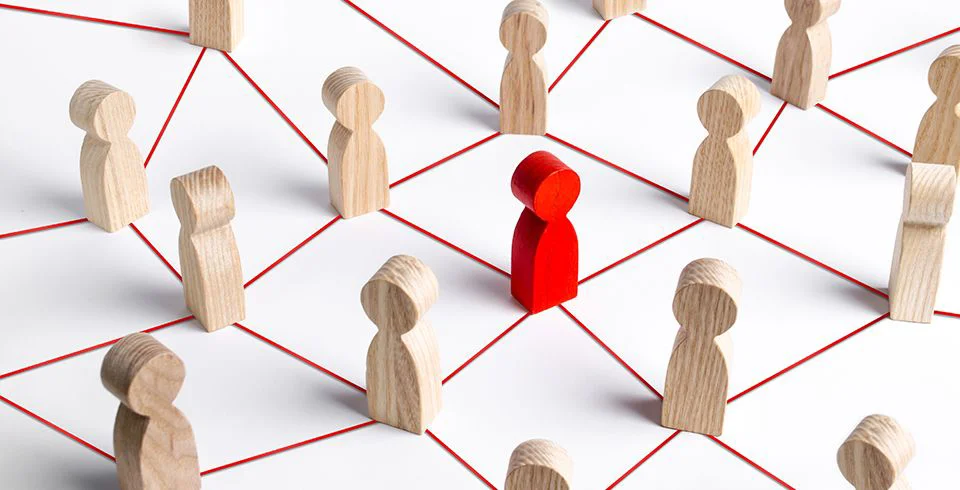 Figura central vermelha conectada a outras figuras de madeira por linhas, simbolizando influência e conexão no marketing digital por meio de vídeo.