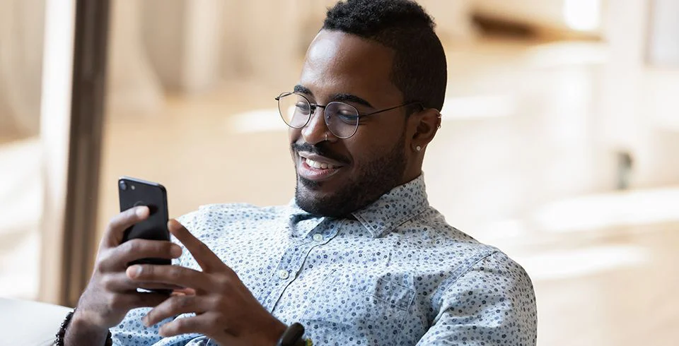 Rapaz usando smartphone em ambiente interno iluminado, representando a importância do vídeo durante o distanciamento social.