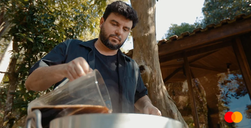 O cervejeiro Junior Botura durante experimento de produção artesanal de cerveja em ambiente ao ar livre, simbolizando tradição e técnica.